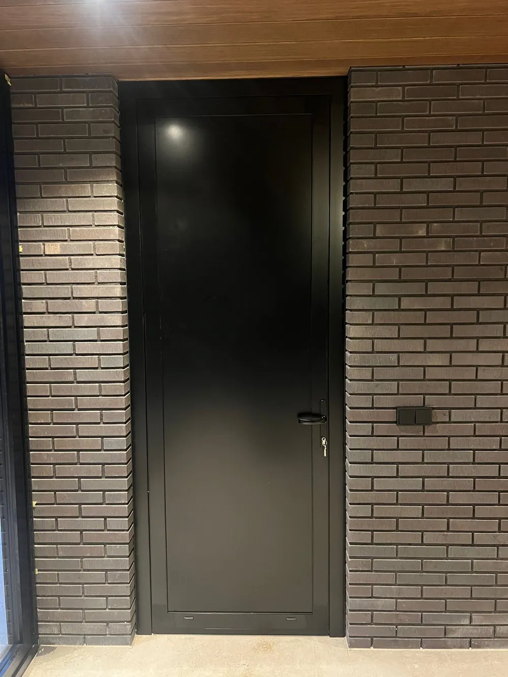 Zwarte aluminium voordeur met bakstenen gevel